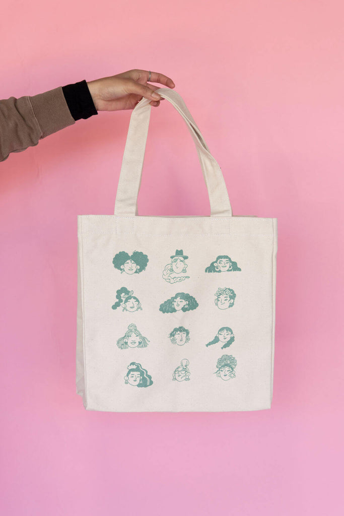 white cotton tote bag with hand drawn faces design in green