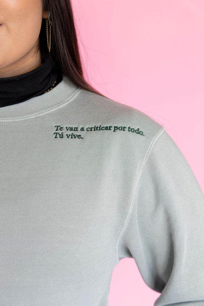 Detail of green embroidered phrase on teal sweatshirt