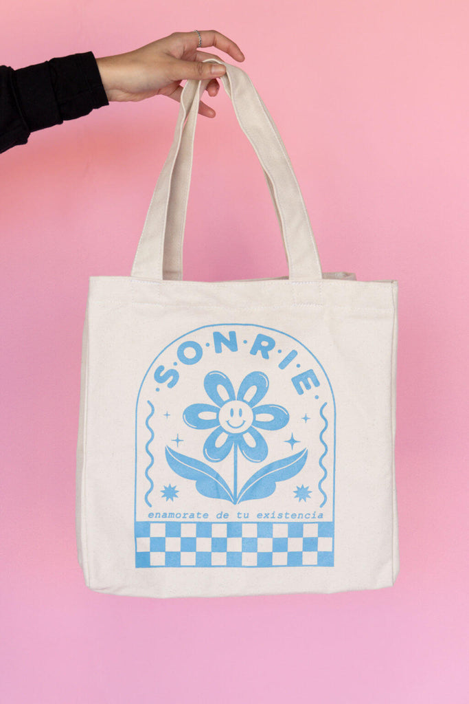 White tote with soft blue flower and  "Sonrie" print